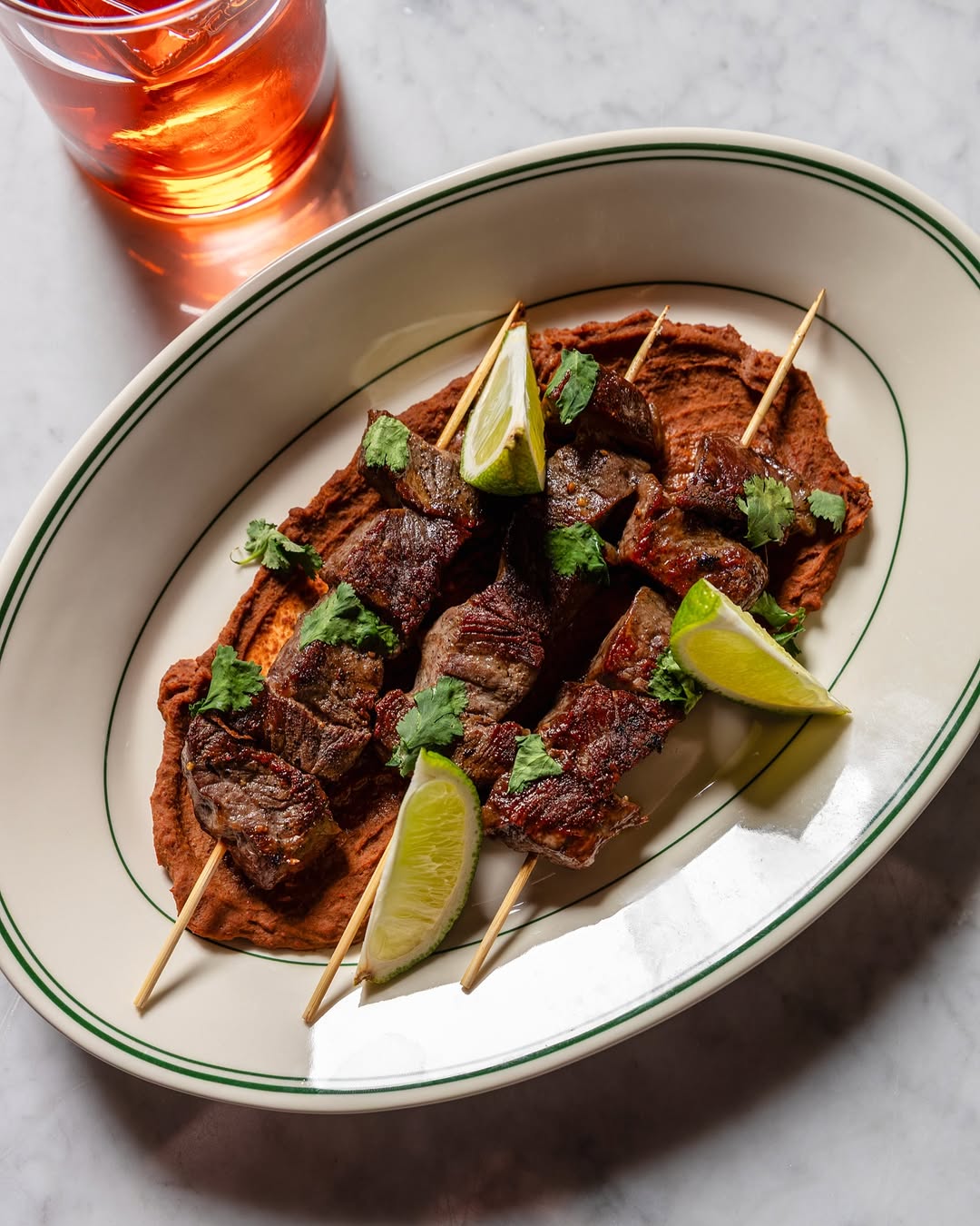 Beef skewers over chile paste, cilantro, lime